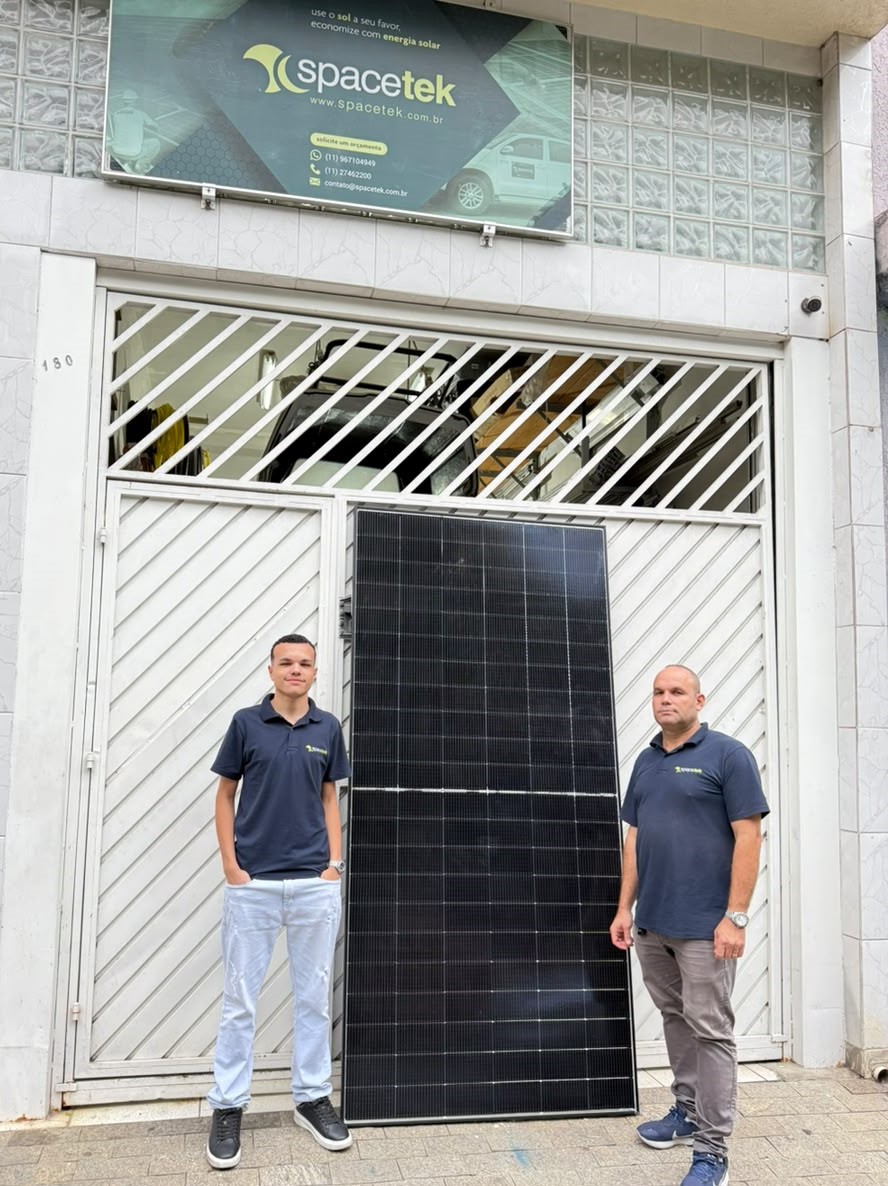 Dois integrantes da Spacetek com um painel solar em frente à sede da empresa