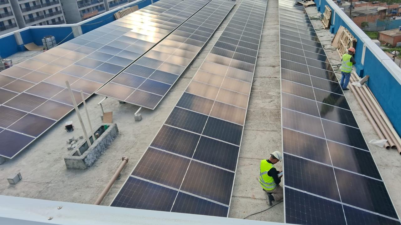 Instalação de painéis solares com profissionais trabalhando na cobertura